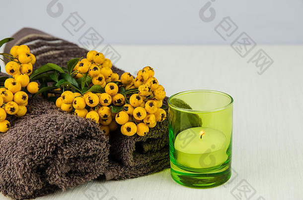 毛巾、蜡烛和黄色浆果植物装饰静物图像