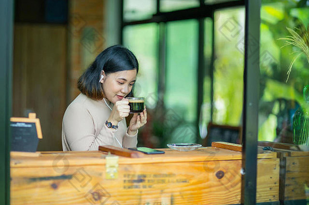 年轻的亚洲女孩在咖啡馆的咖啡厅里喝咖啡