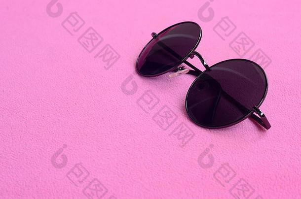 时髦的黑色圆眼镜太阳镜放在柔软蓬松的淡粉色抓绒织物制成的毯子上。fema中的时尚背景图片