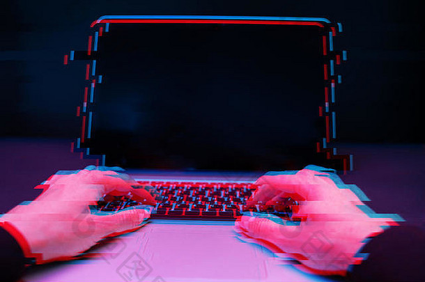 黑屋子里的黑客正在用笔记本电脑打字。具有毛刺效应的图像