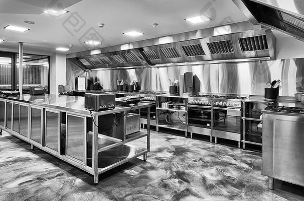 现代全新厨房，配备燃气<strong>灶</strong>、厨具、烹饪桌面和黑白<strong>家电</strong>。