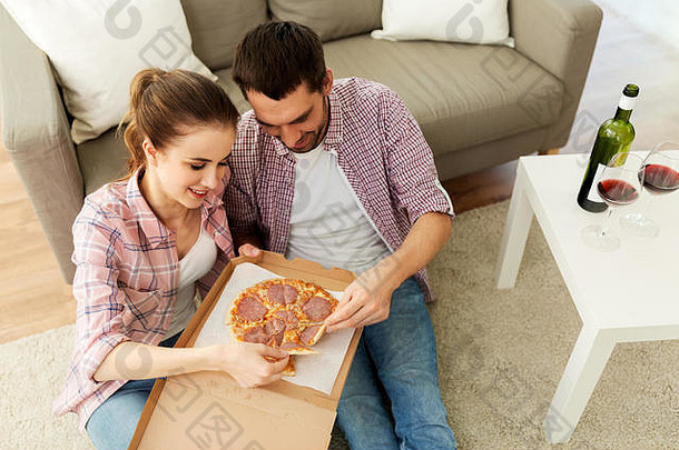 一对喝红酒的夫妇在家吃外卖比萨饼