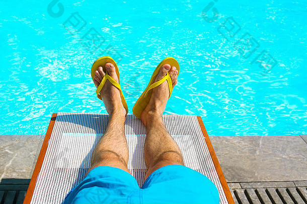年轻人躺在游泳池附近的日光浴床上。暑假与旅游理念