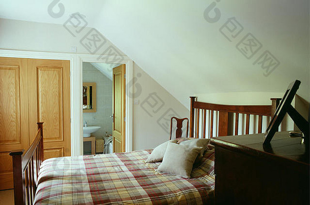 白色阁楼卧室木床上的格子床单，门向卫生间敞开