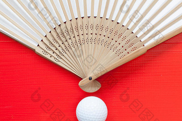 典型的日本手工扇子和红木桌上的高尔夫球