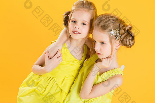 双胞胎女孩坐着椅子黄色的背景