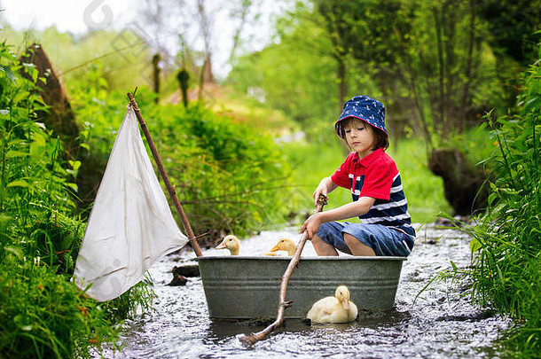 可爱的孩子男孩玩船鸭子河航行boathing孩子有趣的童年幸福概念