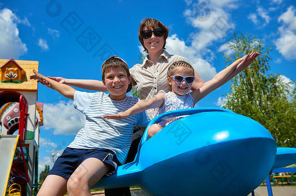 孩子女人飞蓝色的飞机吸引力城市公园快乐家庭夏天假期概念