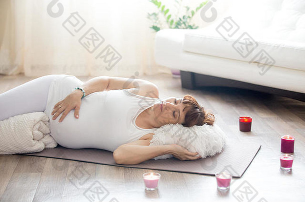 健康生活方式理念。怀孕瑜伽和健身。年轻孕妇在起居室锻炼后休息