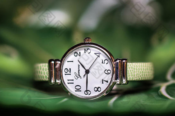 带有绿色表带的现代腕表。抽象绿色背景特写