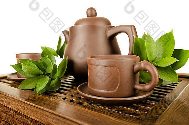 木制三角架上的陶制茶壶和茶杯的静物画，白色背景，与世隔绝