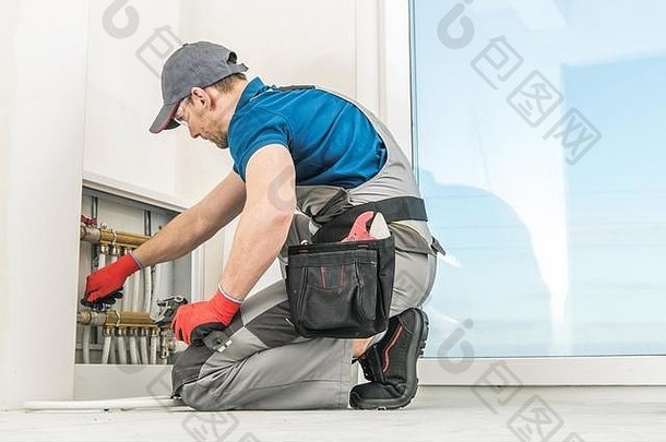 住宅地板上加热管道盒子高加索人管道技术员检查管道阀门