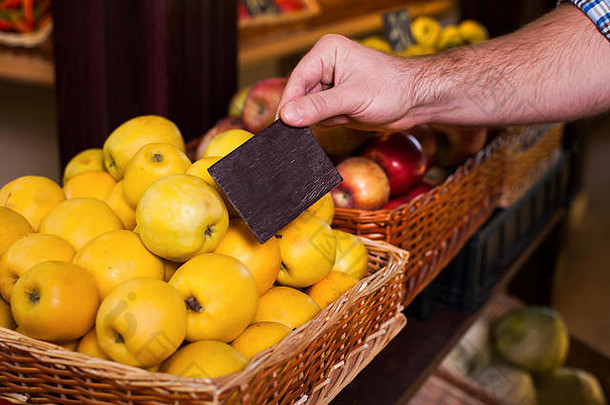 男人的手拿着熟苹果的价格标签。