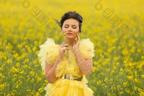 肖像浪漫的浅黑肤色的女人青少年女孩穿黄色的衣服摆姿势场黄色的油菜籽花