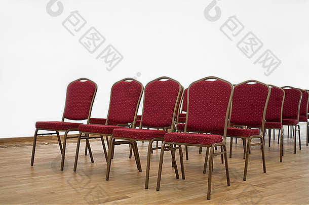 在空荡荡的<strong>会议</strong>大厅里摆放着红色的椅子，上面铺着层压板。