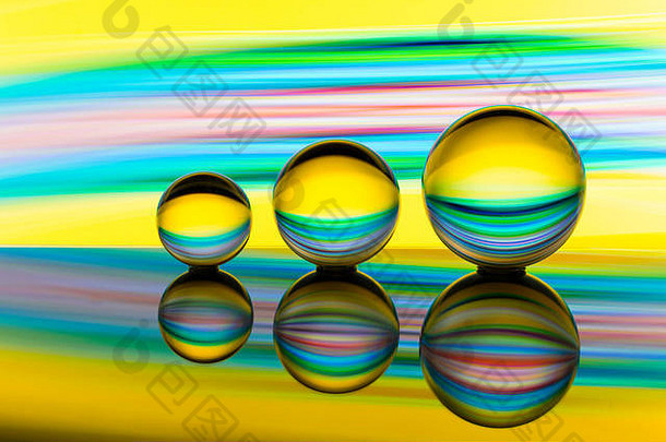 一排三个玻璃/水晶/球体/透镜球，球后有五彩彩虹光画