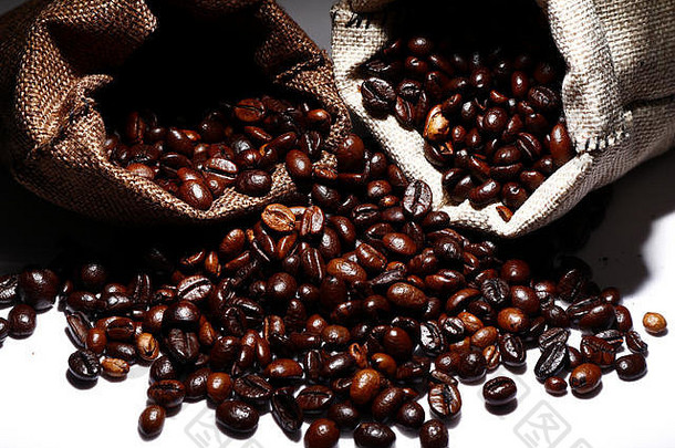 咖啡豆从黄麻袋或小袋中溢<strong>出</strong>的<strong>照片</strong>，拍摄于白色背景上
