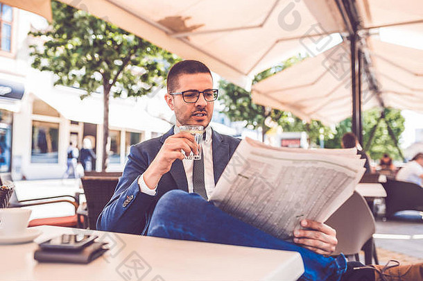 年轻的商人玻璃水手阅读报纸户外咖啡馆