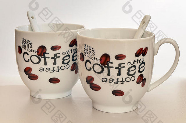 两杯咖啡，用勺子蘸着咖啡豆，上面画着“咖啡”这个词