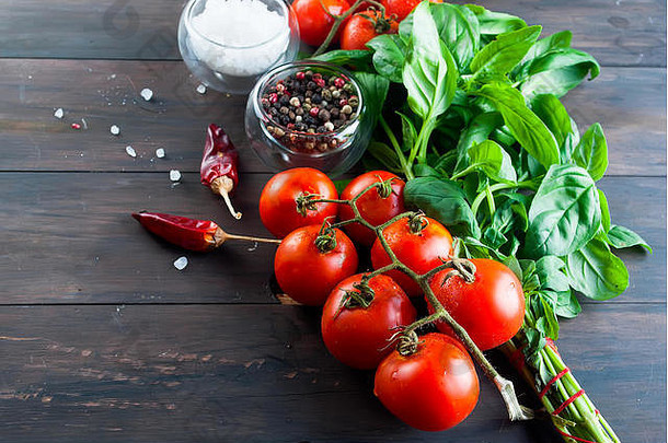 西红柿，一束新鲜的绿色罗勒，胡椒和盐在深色的木头背景上，新鲜的芳香草本接近烹饪草本。拷贝空间