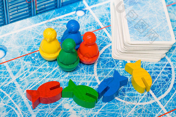 棋盘游戏和儿童休闲概念-红色、黄色、蓝色、绿色的鱼木片图案和儿童玩的扑克牌