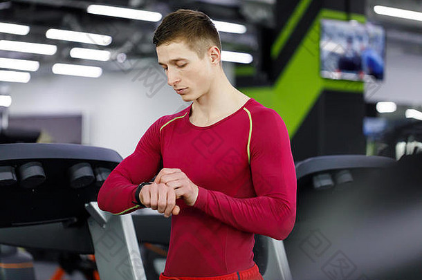 年轻的肌肉发达的英俊的运动员检查体育运动结果聪明的看好锻炼培训会话健身健身房