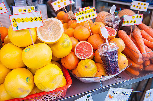 以色列特拉维夫贾法雅福卡梅尔市场新鲜水果饮料果汁摊位橙子粉黄色葡萄柚柑橘胡萝卜石榴标签希伯来伊夫瑞特