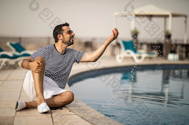 中年阿拉伯男子在游泳池旁享受暑假