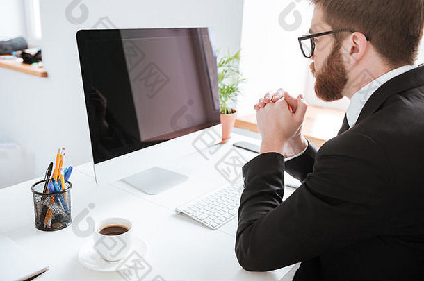 照片年轻的有胡子的商人坐着办公室电脑