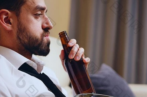 商人下班后在公寓里喝啤酒的侧视图。