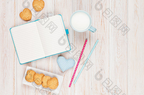 白色木桌上的记事本、牛奶杯、心形饼干和礼物玩具