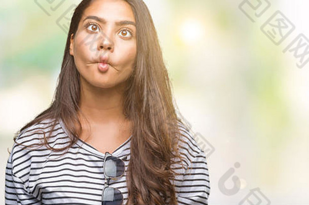 年轻美丽的阿拉伯女人戴着太阳镜在孤立的背景下<strong>做</strong>着<strong>鱼</strong>脸和嘴唇，疯狂而滑稽的手势。滑稽的表情。