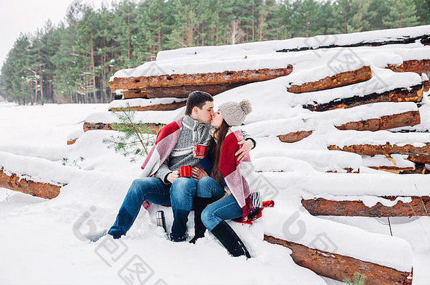 这对微笑的夫妇裹在毯子里，在<strong>冬季</strong>森林的户外喝茶