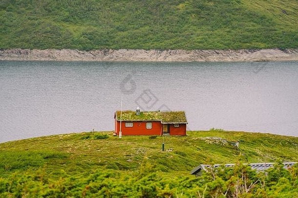 挪威木制避暑别墅，俯瞰风景秀丽的湖泊，挪威，斯堪的纳维亚。乡村湖边的小屋。湖边有泥炭屋顶的小屋。典型的草屋顶