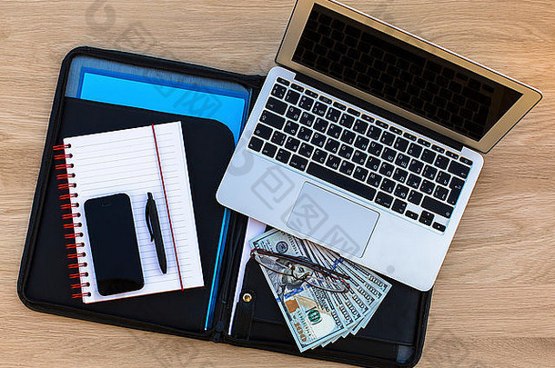 商业概念-文件夹的文件，笔记本电脑，眼镜，记事本与钢笔和百元-一个俯视表上