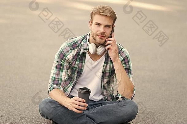 重要电话。电话。听音乐。电子书概念。男式格子衬衫。学生<strong>放</strong>松和充电。咖啡带走。那个家伙在户外喝咖啡。那个人坐在地上。戴着耳机的无忧无虑的学生。