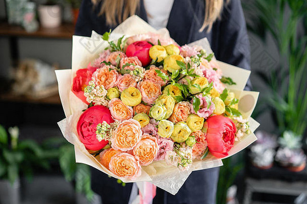 鲜艳的牡丹花束。女人手里拿着一束美丽的鲜花。花店概念。美丽的鲜切花束。花