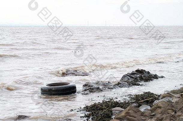 一辆旧轮胎被丢弃的汽车冲上了海边的海岸线