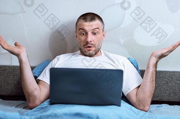 不高兴的男子坐在室内床上使用笔记本电脑<strong>出现问题</strong>