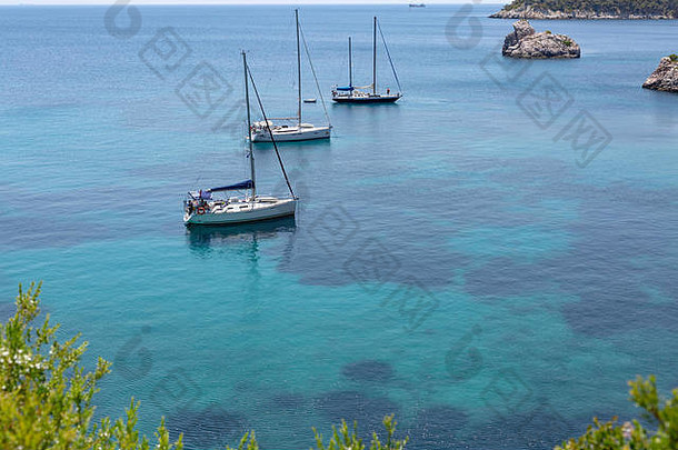 在<strong>希腊</strong>斯科佩洛斯，一个有悬崖和清澈海水的<strong>希腊</strong>岛屿的海湾视图，背景是几艘游艇。