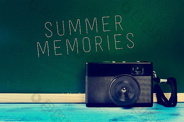 乡村蓝色木质表面上的复古相机和绿色黑板上的文字“夏日记忆”，具有过滤效果