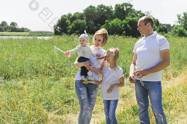 一家人在田野里散步。有肥皂泡的家庭。有两个孩子的家庭。一个成熟的家庭。