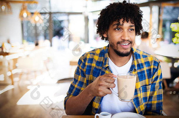 英俊的年轻的非洲男人。喝杯<strong>咖啡咖啡</strong>馆