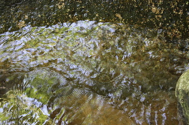 在一个阳光明媚的<strong>夏日</strong>，<strong>清凉</strong>的水在浅溪中的岩石和石头周围流动。