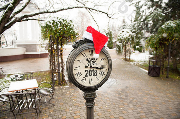 古董街道时钟，标题为“2018年新年快乐”，并在城市公园戴上圣诞老人帽