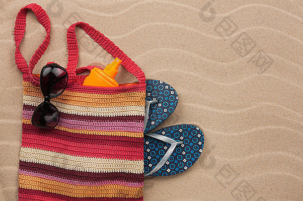 带防晒霜、人字拖、太阳镜的沙滩包。暑假背景