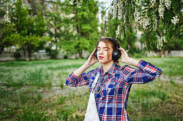 漂亮迷人的女孩时髦耳机的肖像。她喜欢音乐。暖色调。幸福生活的概念。