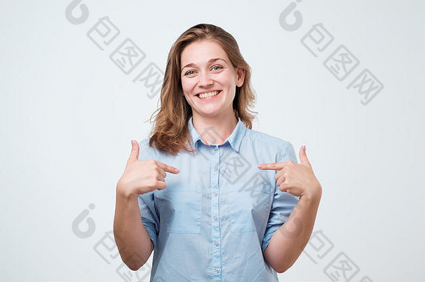 美丽的欧洲女孩快乐地用食指抚摸着自己。她为自己的考试成绩感到骄傲。在灰色背景上隔离的工作室照片