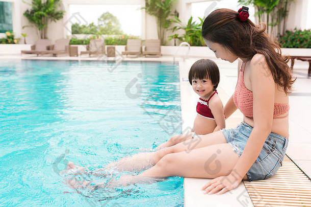 妈妈和小女孩在游泳池里玩得很开心。暑假及假期概念