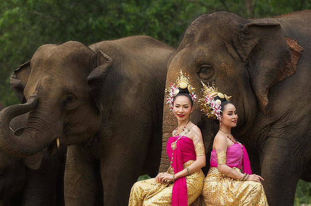 泰国清迈，一位美丽的泰国农村妇女穿着泰式服装，带着大象